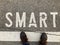 Man standing in front of smart word inscription on asphalt