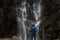 Man standing in front of waterfall, traveller enjoying nature