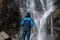 Man standing in front of waterfall, traveller enjoying nature