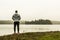 Man standing at lake of two rivers algonquin national park watching ducks Ontario Canada on a grey morning atmosphere