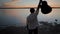 Man standing at lake waterfront and raising guitar up in the air at glorious golden sunset, Torrevieja Pink lake in