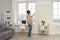 Man standing in living-room and adjusting air conditioner settings with remote control