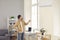 Man standing in living-room and switching on air conditioner with remote control