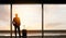 Man standing and looking out at the airport window while waiting for flight departure