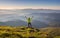 Man standing on the mountain peak with raised up arms against