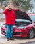 man standing near broken car with opened hood calling help