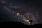 A Man is standing next to the milky way galaxy pointing on a bright star, Long exposure photograph, with grain