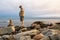 A man standing next to the stone cairn on the ocean shore in Connecticut, USA