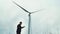 A man standing next to a windmill, a cloudy sky. Renewable energy sources. Blade