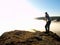 Man is standing on the peak of sandstone rock in national park Saxony Switzerland and watching over the morning misty valley