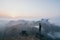 Man standing on the rock overlooking tropical mountains at sunrise foggy morning in Hpa-an, Myanmar