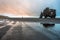 Man standing on the sandy textured beach at low tide looking towards the basalt/volcanic rock