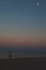 Man standing at sea beach looking at moon