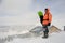 Man standing with the snowboard in hands on the hill near the ho