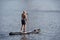 Man standing on a stand up paddle board is paddling on a lake