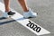 Man standing on stepping on white line with year 2020 sign