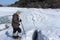 Man standing with sticks at a crack on a melting river