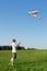 Man standing on summer meadow and flying kite