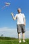 Man standing on summer meadow and flying kite