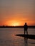 a man standing on top of a body of water in the middle of the sunset