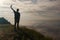 A man standing on top of a hill and looking at his mobile phone in his hands.Silhouette of the traveler.