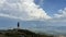 Man standing on top of the mountain relaxing and enjoying beautiful summer mountain landscape. A panoramic view of the