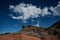 A man standing under a cloud, on a colourful vulcanic rock, Tenerife, Spain.