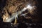 Man standing under the light in the mountain cave. Extreme adventure travel concep