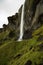 A man in standing under waterfall in Iceland. Powerful and long waterfall. Beauty of the nature. travel concept