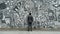 Man standing before a vast mural filled with doodles, contemplating modern street art. urban, monochrome, creative