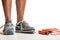 Man standing wearing worn out pair of trainers, and skipping rope on the ground - health fitness and training concept image