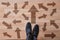 Man standing on wooden floor with arrows pointing in different directions. Concept of choice