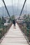 Man standing on wooden suspension bridge in a mountain village of Laos