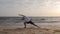 Man standing yoga pose utthita parsvakonasana on background waves on sea beach