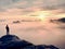 Man stands alone on the peak of rock. Hiker watching to autumn Sun at horizon