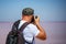 A man stands back with a backpack taking photos of nature, salty pink lake