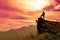 The man stands on a cliff top and orange sky