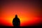 a man stands in a dark place with a red and orange sky generated by ai