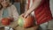 A man stands in front of the table and takes out seeds from a pumpkin. He puts them in a bowl