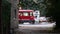 Man stands near the tram tracks. A red tram passes by a human. A man picks up