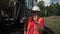 man stands near undercarriage of crawler mounted excavator and talks on phone