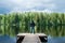 Man stands on the pier of a beautiful lake, panoramic photo. The concept of freedom and independence, a symbolic photo of the