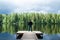 Man stands on the  pier of a beautiful lake. Young man enjoying life,  Man welcomes the beauty of nature, he is happy