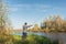 Man stands on the shore with a fishing rod. Angler in a jacket with a fishing rod stands on the river bank