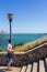 A man stands on the stairs of mount Mithridates and looks at the summer landscape with views of the sea and the Crimean bridge.