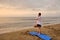 Man stands in tree pose asana at beach