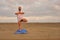 Man stands in tree pose asana at beach