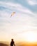 Man starting to fly bright kite in sunset sky over the mountain. Successful startup concept image