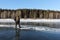 Man stepping over a crack on thin ice of a frozen river