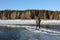 Man stepping over a crack on thin ice of a frozen river